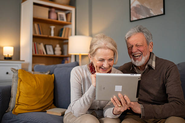 istock Happy senior couple laughing and using digital tablet at home 2214235884