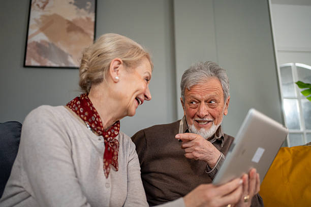 istock Happy senior couple laughing while using digital tablet at home 2214235911