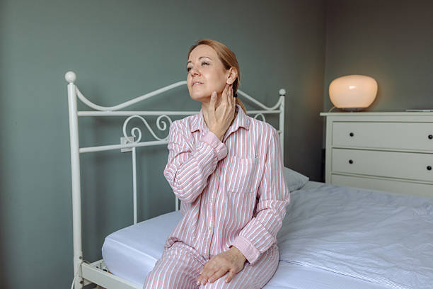 istock Woman in striped pajamas feeling discomfort while sitting on a bed 2214236449