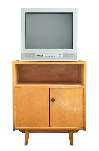 An old television set isolated on a white background stands on a vintage bedside table from the 1990s, 1980s.