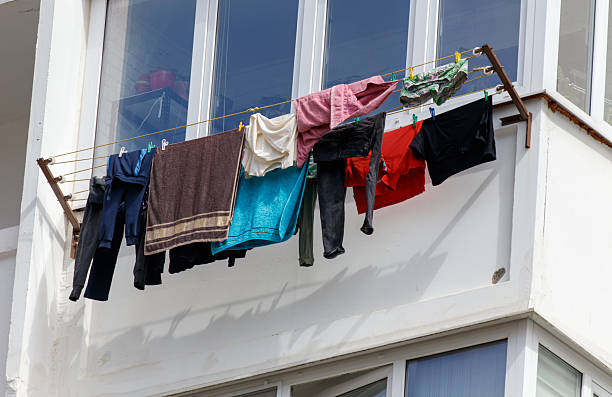 A line of clothes hanging on a clothesline outside. The clothes are of different colors and sizes