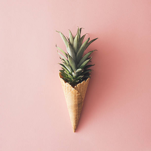 istock Ice cream cone with pineapple leaves on pastel pink backround.Fruit and candy concept.Flat lay. 2214257321