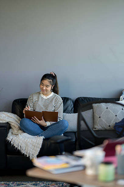 istock Young Woman Writing in Notebook on Comfortable Couch in Modern Setting 2214257486