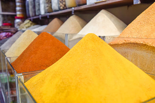 Colorful spices, herbs, and natural materials fill sacks and baskets on display at an outdoor market. The scene captures the essence of traditional Moroccan trade.