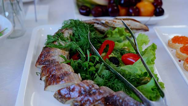 istock Grilled fish slices lying on white plate, accompanied by dill, lettuce, cherry tomatoes, black olives, bell peppers, presenting vibrant mediterranean style seafood arrangement 2214258083