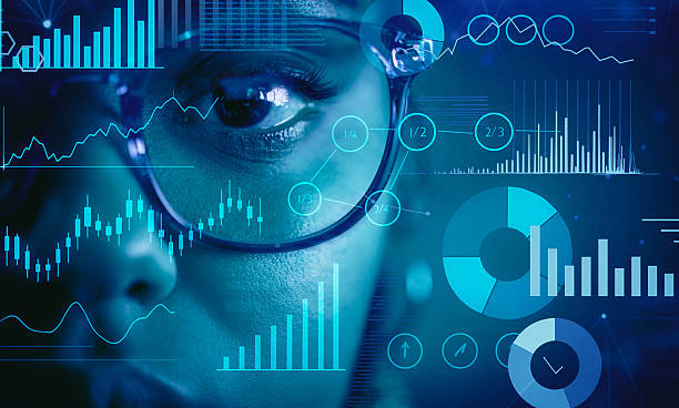A close-up of a professional examining data through a futuristic digital interface featuring charts, graphs, and analytics in vivid blue tones.