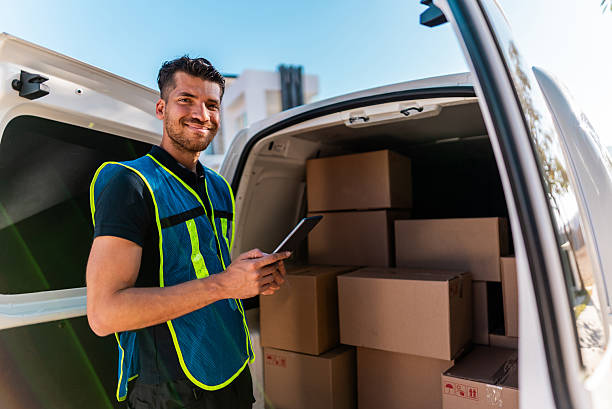 istock Portrait of young delivery man checking packages at van 2214260055