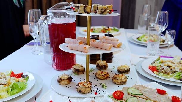 istock Displaying a three tiered serving stand filled with stuffed mushrooms, rolled ham, canapes, caesar salad, and a pitcher of red juice, creating an elegant banquet setting 2214261016