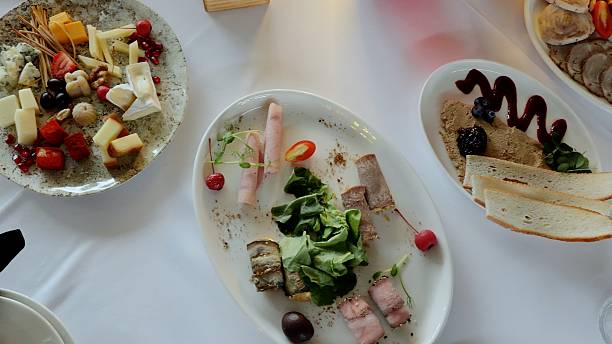 istock Gourmet spread featuring artisan cheeses, cold cuts, pate, fresh fruits, and rustic bread arranged elegantly on pristine white plates at upscale catered gathering 2214262176