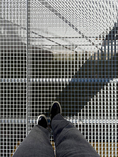 istock High angle view of legs standing on metallic grid 2214264424
