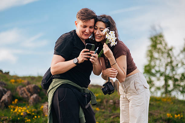 Happy teenager tourist couple looking at phone and taking selfie in nature, beside river.