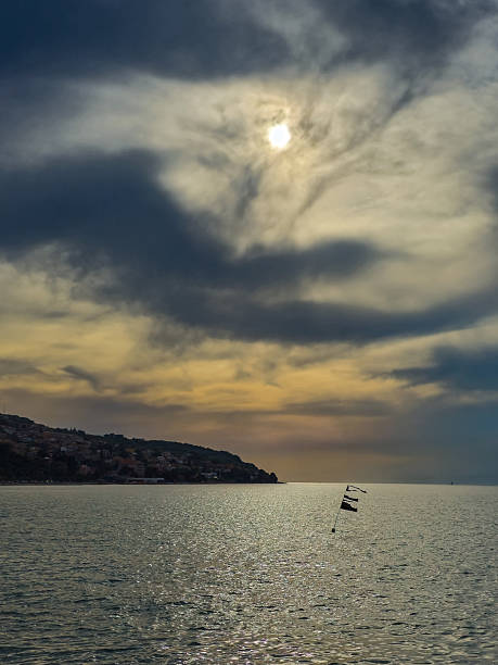 Section of the sky with altocumulus and distant storm clouds over the water surface of sea at autumn morning