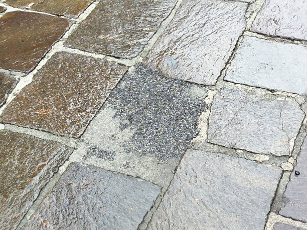 istock Wet cobblestone street with water puddle on weathered surface 2214272399
