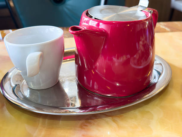 Red teapot with white cup on silver tray, lifestyle