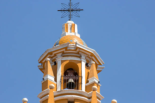 Majestic bell tower of the iglesia de nuestra señora de los remedios, cholula, puebla, mexico, displaying vibrant yellow and white colors against a clear blue sky