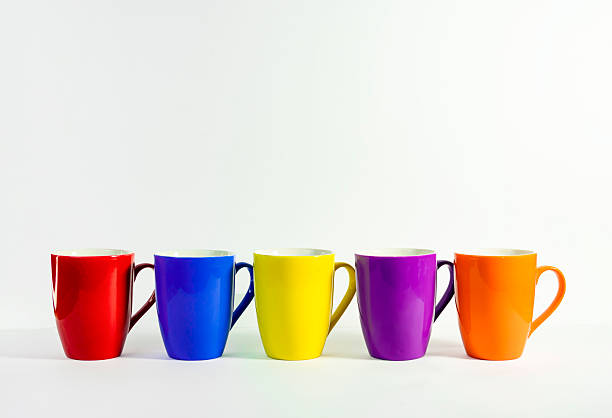 Black and white ceramic mugs on yellow background, flat lay. Space for text