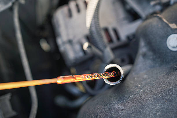 A car engine is being checked for oil. A long, thin, orange stick is inserted into the engine