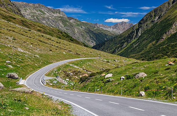 Silvretta-Bielerhohe High Alpine Road running through a green mountain valley in Vorarlberg, Austria. Scenic summer view with dramatic alpine slopes and clear blue sky. Quiet road in a remote mountainous landscape.