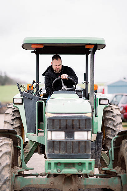 A Caucasian man in his 30's turns on a tractor while working on the rutabaga farm his family owns in rural Oregon, USA.