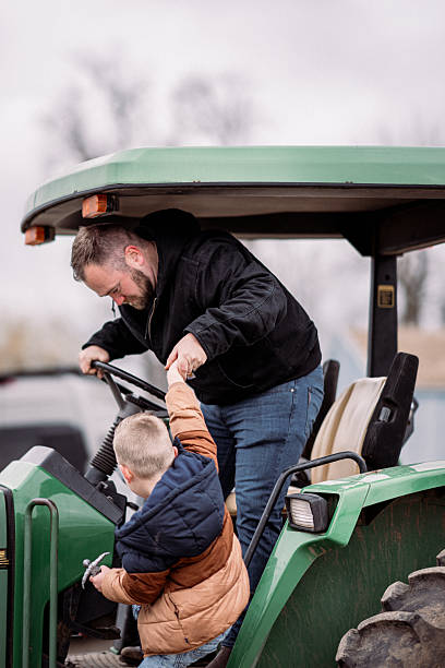 istock Farmer helping his son get onto tractor 2214285883