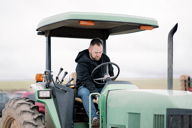 A Caucasian man in his 30's turns on a tractor while working on the rutabaga farm his family owns in rural Oregon, USA.