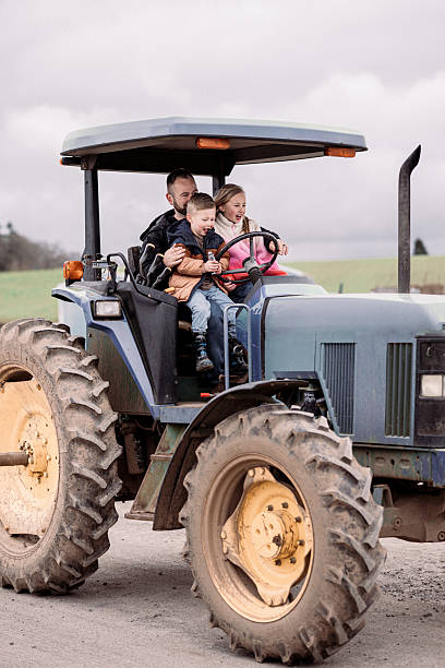 istock Siblings riding on a tractor with their dad 2214285893