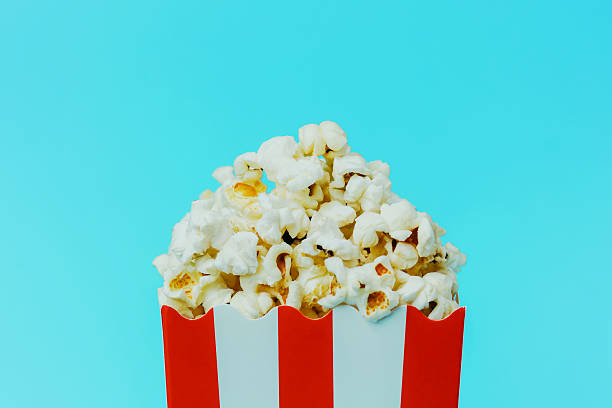 istock Enjoying fresh popcorn in a brightly colored container against a blue background 2214287695