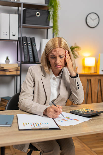 istock Upset mature businesswoman using calculator feeling worried about financial problem at office desk 2214291493