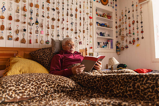 Senior man reading a book in bed in his cozy bedroom
