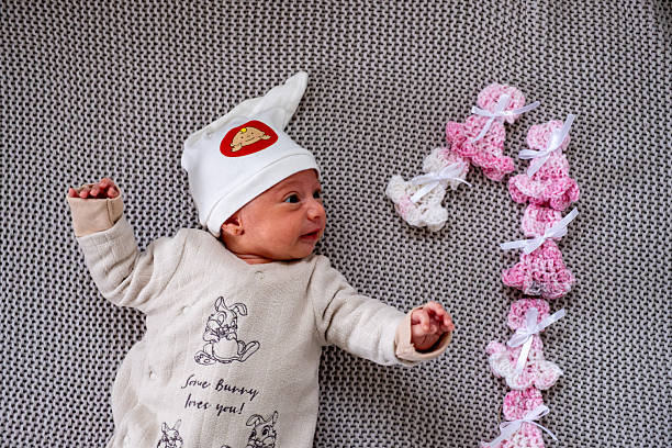 Adorable Newborn Wearing Hat on Knit Blanket with Pink Decorative Elements
