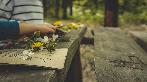 istock Children creating handmade flower crafts using cardboard, drawing vases and attaching real spring blossoms. Creative outdoor activity on a rustic wooden table in the forest 2214311360
