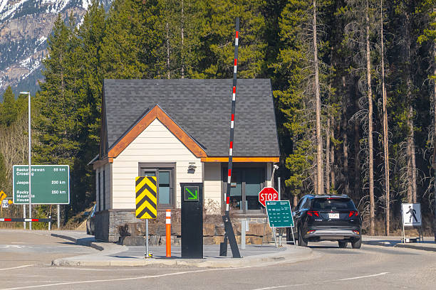 Jasper, Alberta, Canada. May 9, 2025. A border crossing station stands amidst a forest, with a vehicle approaching. Signage indicates distances to Saskatchewan Crossing, Jasper and Rocky Mountain