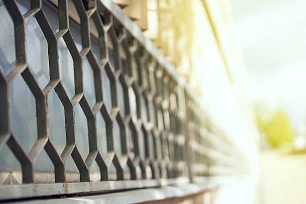 Metal hexagonal honeycomb grille on a tall sunlit window, creating striking geometric shadows and modern architectural detail.