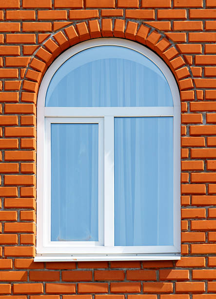 A window with a white curtain and a clear blue sky outside