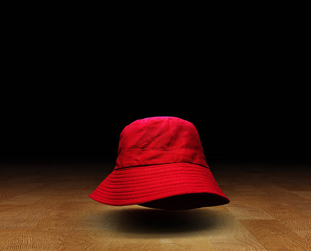 istock Red bucket hat on wooden floor, black background. 2214314371