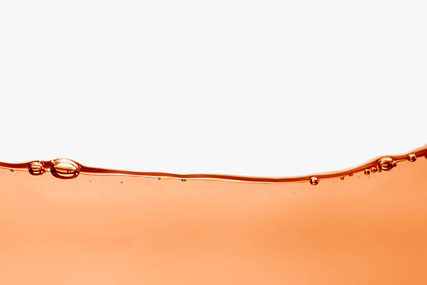 Abstract vivid orange liquid surface with gentle waves and air bubbles, isolated on a clean white background. Ideal for use in beverage ads, wellness branding etc.,