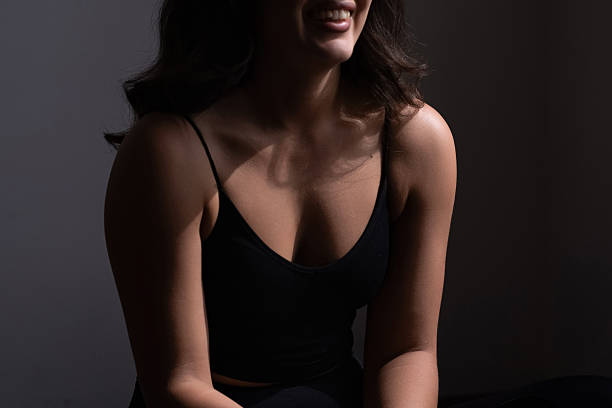 istock A woman sits on the floor in a dark space, stretching her legs while preparing for an evening workout 2214318156