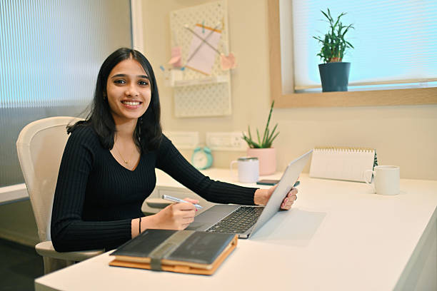 istock Smiling young female professional looking at camera while working on laptop 2214318230