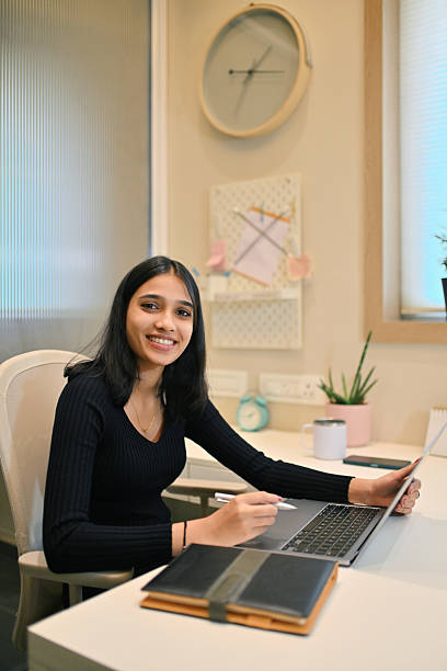 istock Smiling young female professional looking at camera while working on laptop 2214318331