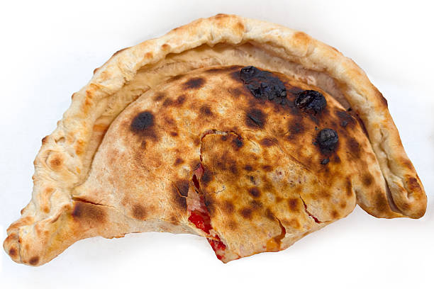 Baked closed type of pizza that is folded in half, so called calzone pizza, top view on a light background
