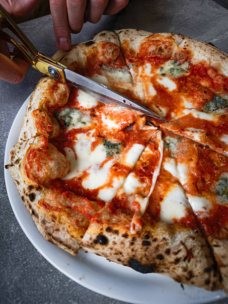 istock Delicious pizza being sliced with scissors on a plate showcasing melted cheese and toppings concept. copy space 2214323964
