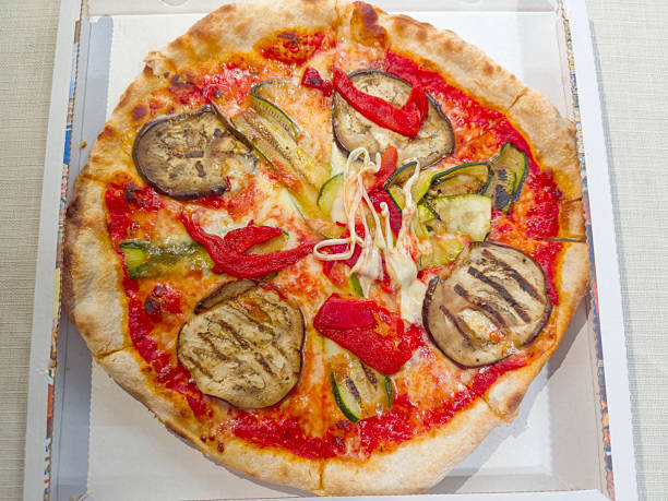 Baked round vegetarian pizza with different vegetables served in a cardboard box