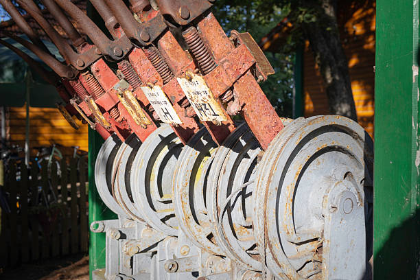 A row of old, rusty gears are lined up next to each other. The gears are all different sizes and appear to be in various stages of disrepair. Scene is one of decay and neglect