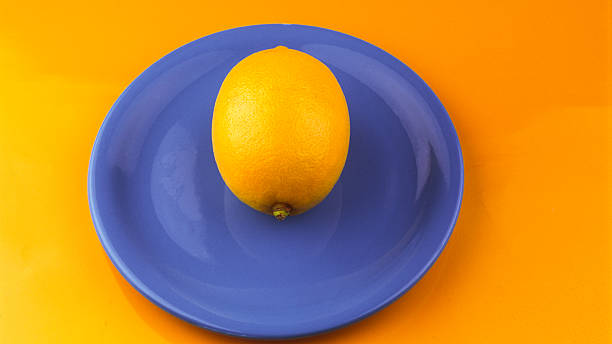 istock Yellow lemon on a blue plate on a yellow background. 2214329253