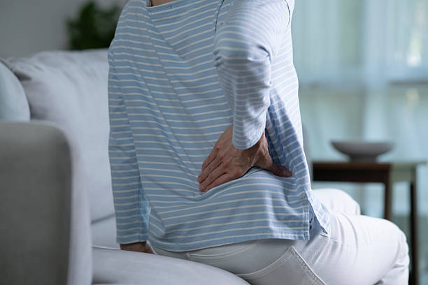 istock Senior woman on sofa feeling and suffering from back pain. 2214331178