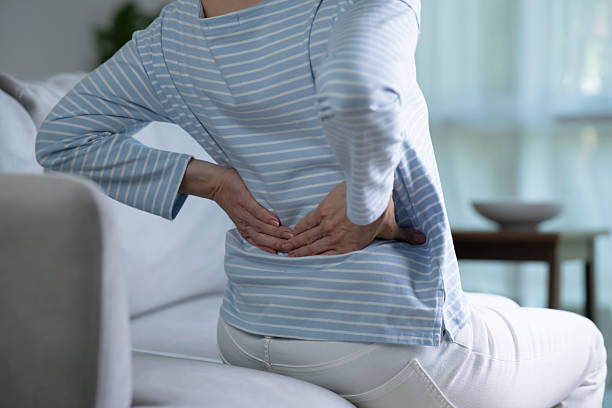 istock Senior woman on sofa feeling and suffering from back pain. 2214331300