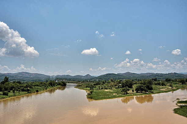 This photo captures the serenity of the Đăk Bla River, which gently winds through Kon Tum Province in central Vietnam. Surrounded by lush vegetation and bordered by rolling hills on the horizon, the river reveals a typical panorama of the Central Highlands. The contrast between the ochre-colored water, the result of alluvial deposits, and the blue sky punctuated by fluffy clouds creates a natural composition of great beauty.The Đăk Bla is a vital artery for the region. It irrigates the surrounding crops, supports local communities, and serves as a hub for life, transportation, and fishing. In the apparent calm of this scene, we perceive the river's discreet power and the richness of its ecosystem.From the Kon Klor Bridge, this view opens like a peaceful canvas, where nature reigns supreme. It invites us to slow down, observe, and experience the tranquility of a Vietnam still untouched by the hustle and bustle of the city. A moment suspended in an authentic rural setting.