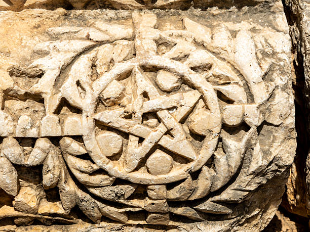 A close-up image of a five-sided star intricately carved into stone at the archaeological site of Capernaum, Israel. The weathered detail highlights the artistic and symbolic elements preserved in the ruins of this historic village on the Sea of Galilee. Ideal for editorial use in topics related to ancient art, biblical history, archaeology, and cultural heritage.