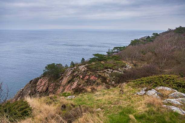 Dramatic rocky coastline with a small white lighthouse on the edge of the cliffs in Kullen, Sweden.