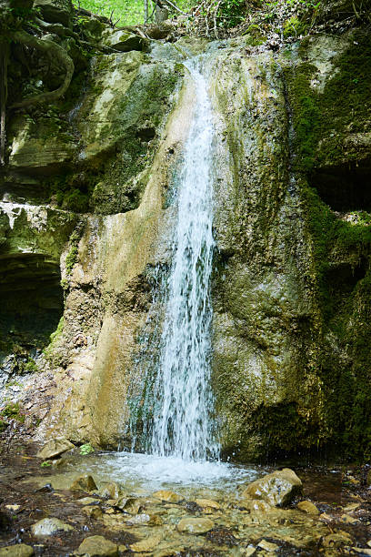 istock A small waterfall flows down from a rocky cliff. The water is clear and the stones are brown. The landscape is calm and serene 2214339508
